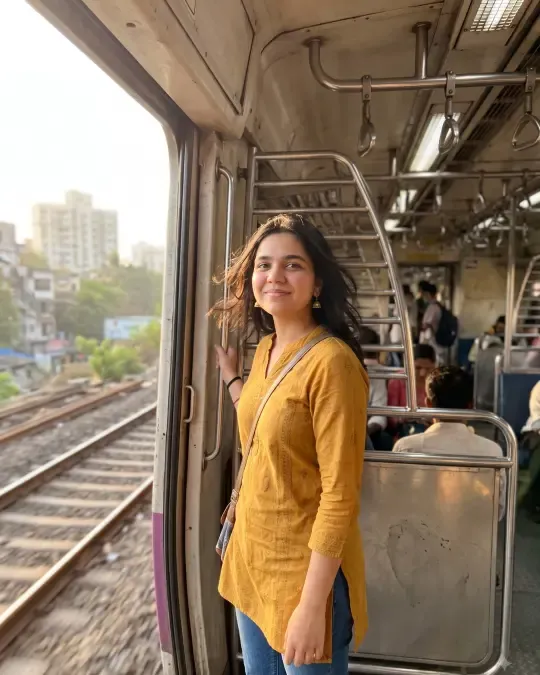 AI-generated image of Rutu in a mustard cotton kurta and jeans at a local train door